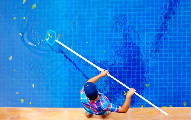 A pool cleaning professional cleaning a swimming pool